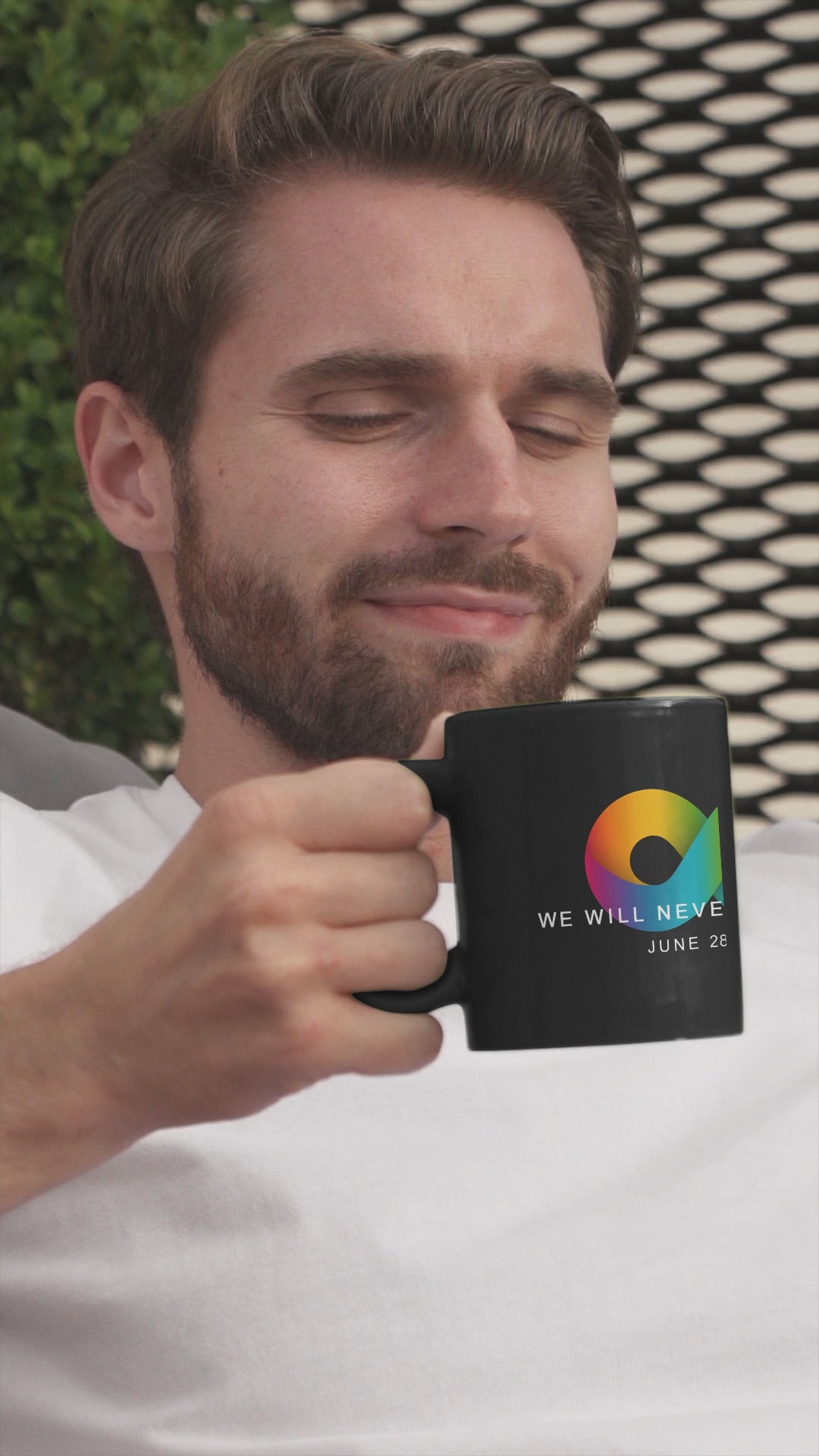Man Drinking from a  black ceramic Stonewall mug  with an rainbow infinity sign wtih the wording We Will Never Be Silent, June 29, 1969